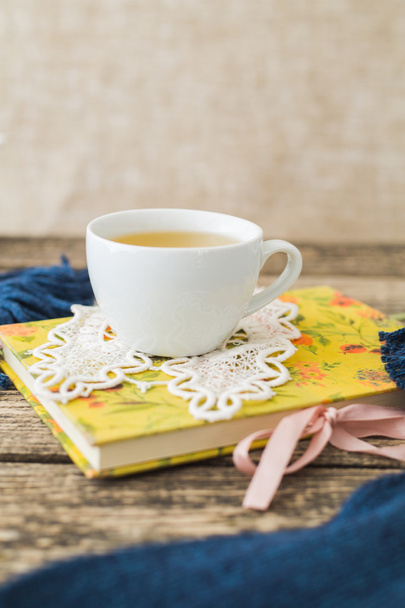 Taza blanca de té de manzanilla y libro en la mesa
. - Foto, imagen