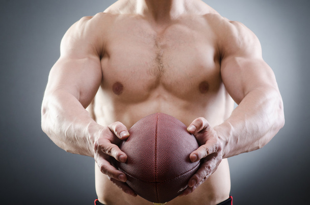 Muscular man with american football - 写真・画像