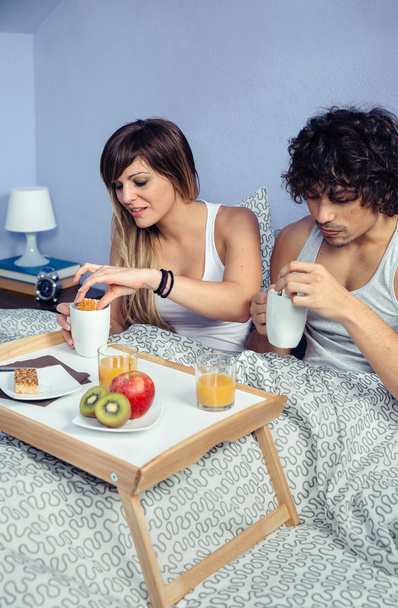 Coppia che fa colazione a letto servita su vassoio
 - Foto, immagini