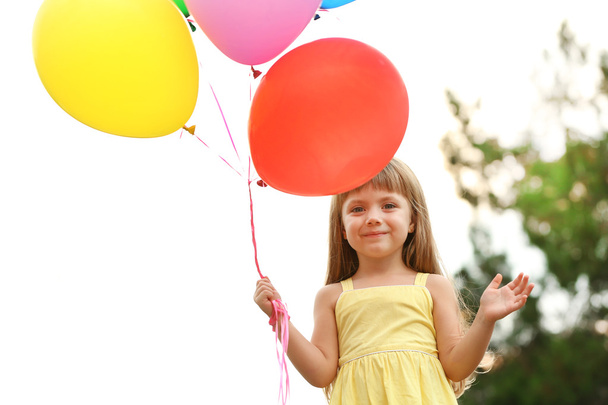 Little girl with balloons outside - 写真・画像