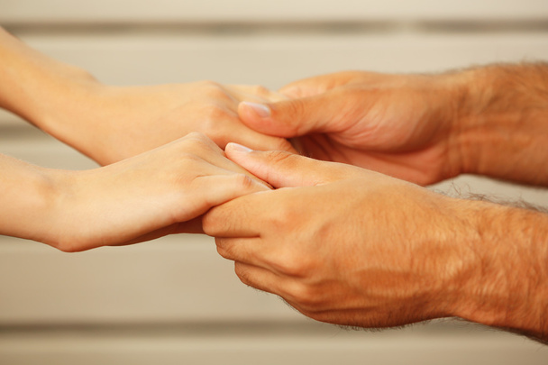 Konzept der Unterstützung - Mann und Frau halten Händchen vor weißem Holzhintergrund - Foto, Bild