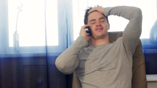 Ενηλίκων άνδρα που, καθισμένος σε μια καρέκλα που μιλάτε στο τηλέφωνο - Πλάνα, βίντεο