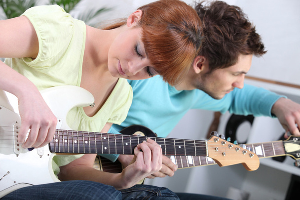 Young couple tuning and playing guitar - Fotó, kép
