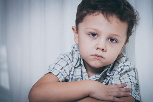 Portrait of sad little boy sitting near the window - Zdjęcie, obraz