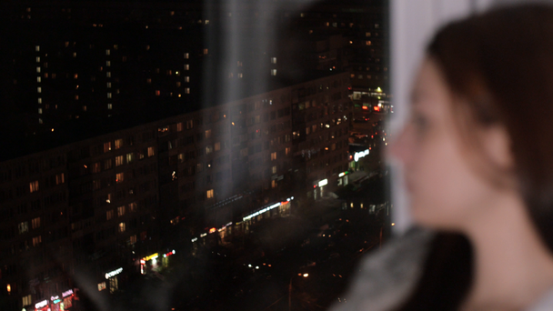 Mulher triste senta-se na soleira da janela, olhar para a cidade da noite
 - Filmagem, Vídeo