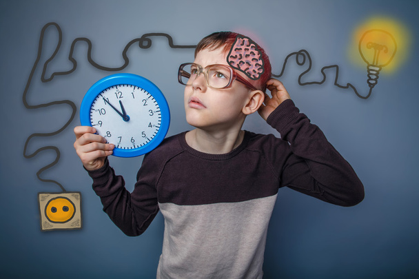 Teenage boy scratching his head and holding a clock booster char - 写真・画像