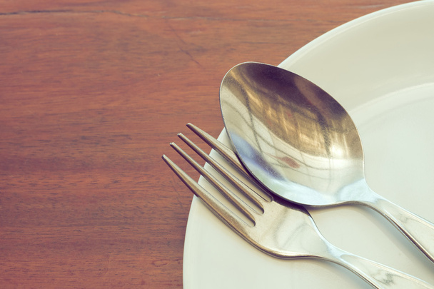 посуда, накрытая на деревянный стол с тарелкой, ложкой и вилкой
 - Фото, изображение