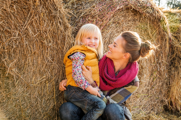 Portrait of woman and happy child sitting on hay on farm - Photo, Image