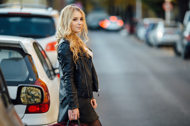 Pretty young woman walking on the street with cars - Fotoğraf, Görsel
