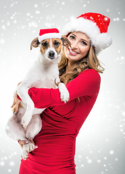 Жінка в капелюсі Санта тримає собаку
 - Фото, зображення