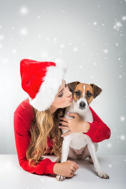 Nainen jouluhatussa suutelemassa koiraa
 - Valokuva, kuva