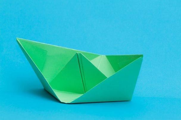 Barco de papel verde sobre fundo azul
 - Foto, Imagem