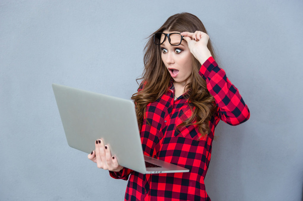 Portrait of shocked girl with opened mouth using laptop - Photo, Image