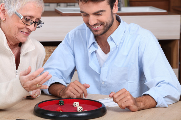 Young man playing dice with older woman - Foto, Imagem