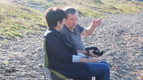 Volwassen liefhebbers zit op het strand en genieten van het uitzicht - Video