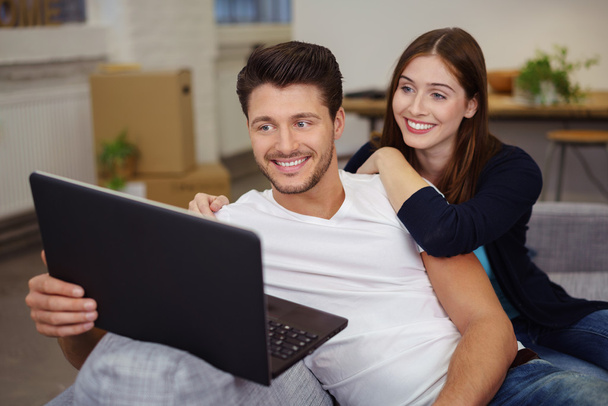Smiling attractive couple sharing a laptop - Fotó, kép