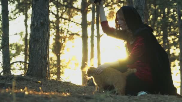 rothaarige Hexe streichelt eine Ingwerkatze im Wald - Filmmaterial, Video