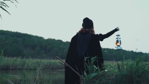 női visel köpenyt, lámpa álló gazdaság a tónál - Felvétel, videó