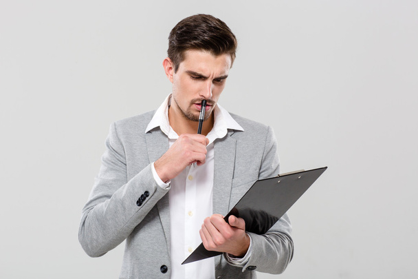 Concentrated young businessman planning and writing in clipboard - Foto, imagen