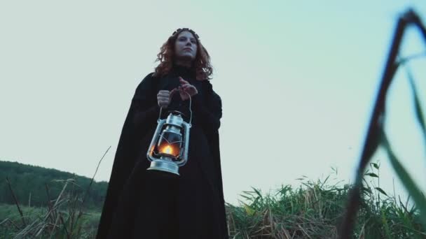 female wearing old-fashioned clothes holding a lamp posing outdoors - Footage, Video