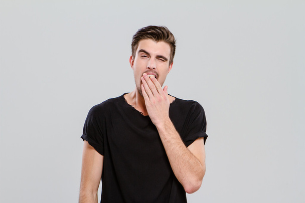 Exhausted young guy yawning and closing mouth by hand - Φωτογραφία, εικόνα