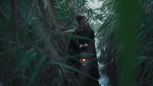 régimódi hölgy tartja a lámpa wading átmenő a Nádas és mocsár - Felvétel, videó