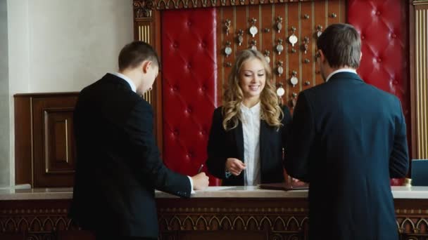 Check into a hotel. Businessmen filled with documents at the reception of the hotel - Filmati, video
