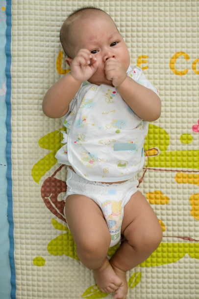 Asian baby sleeping is suck white bed linen. - Foto, Imagem