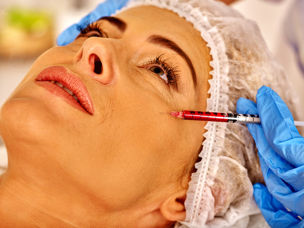 Woman middle-aged in spa salon with beautician. Woman giving botox injections. - Photo, Image