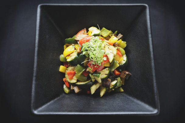 Подготовленный салат в черной тарелке
 - Фото, изображение