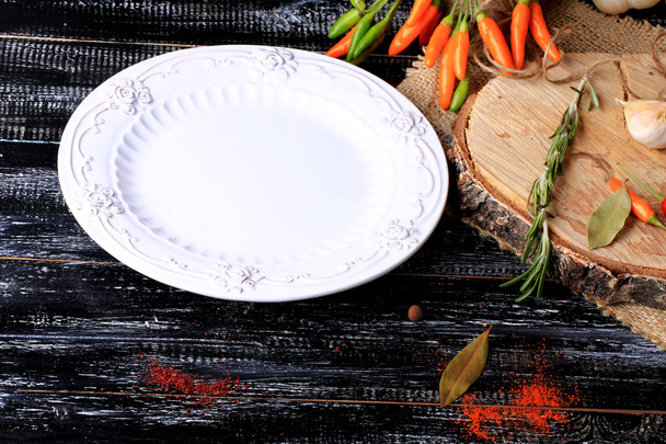 empty white plate hot peppers on a dark old wooden background spices retro vintage style - Foto, Imagem