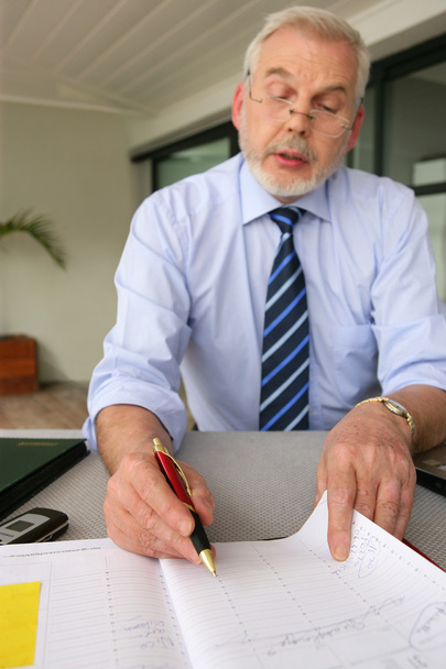 Senior businessman filling in diary - Fotó, kép