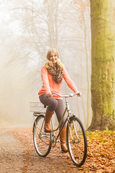 Happy active woman riding bike in autumn park. - 写真・画像