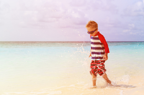 Kleiner Junge planscht Wasser am tropischen Strand - Foto, Bild