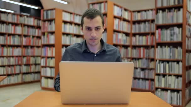 Genç yakışıklı adam oturur ve dizüstü bilgisayarda çalışır - Video, Çekim