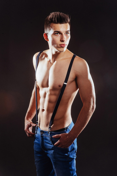Portrait of a man with nude torso fitness standing in jeans with - 写真・画像