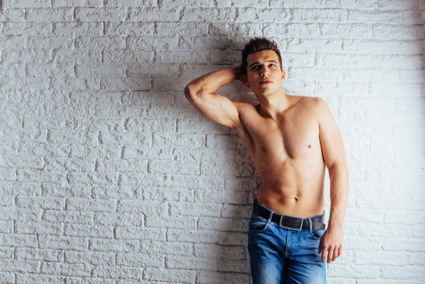 Healthy young guy posing near a white brick wall. - Photo, Image