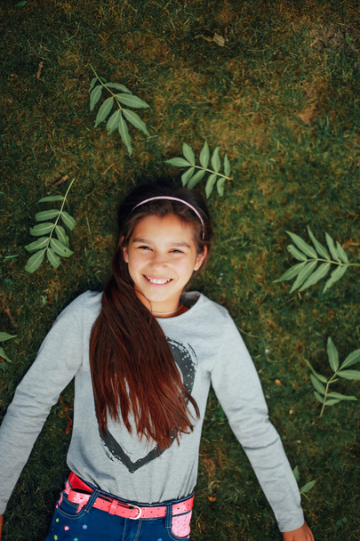 Beautiful little girl lying on the grass and smile - Fotografie, Obrázek