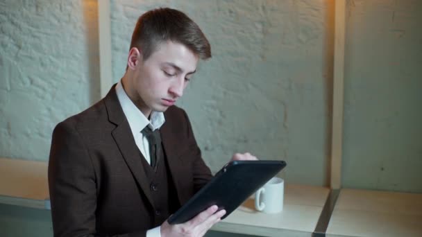 serious Businessman working on tablet computer in the cafe and looking at camera - Кадры, видео