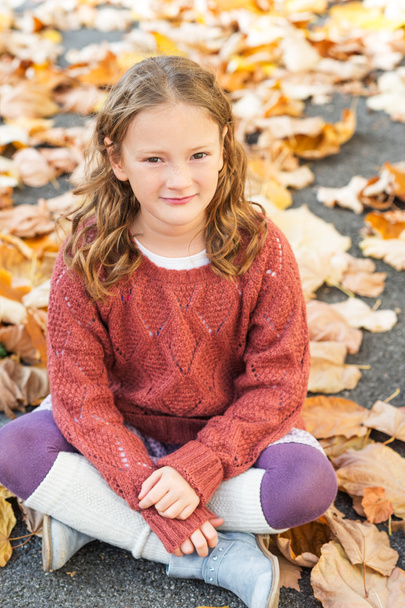 Autumn portrait of a cute little girl with curly hair, wearing terracota pullover, leg warmers and blue boots - 写真・画像
