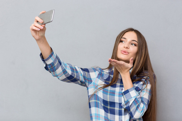 Beautiful girl making selfie sending an air kiss  - Valokuva, kuva