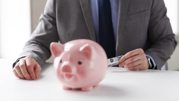 close up of man putting money into piggy bank - Πλάνα, βίντεο