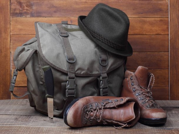 Rucksack mit alten Stiefeln, Messer und Hut auf Holzgrund - Foto, Bild