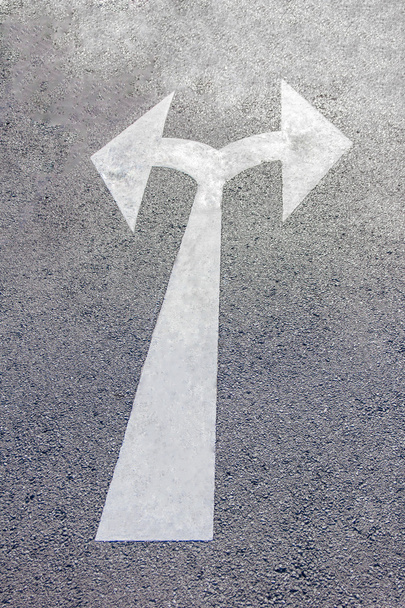 Kétirányú nyíl szimbólum egy fekete aszfalt útfelületen. - Fotó, kép