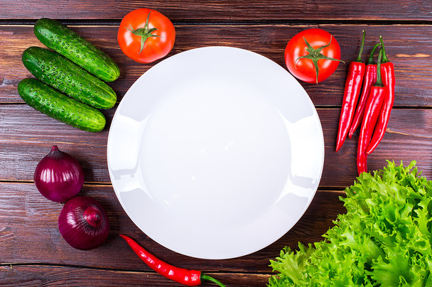 Plate, tomatoes, cucumbers, onions, pepper, greens - Фото, изображение