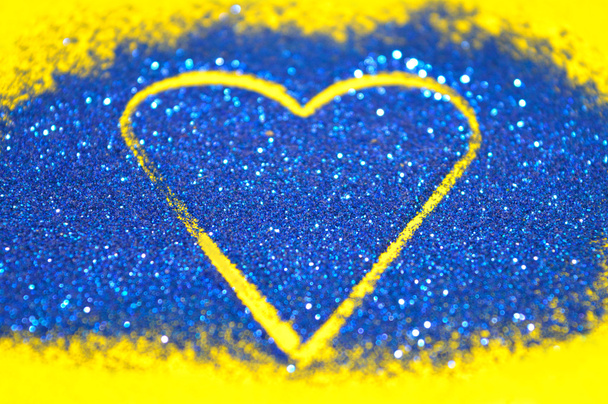 Fond abstrait flou avec coeur de paillettes bleues scintillent sur la surface jaune
 - Photo, image