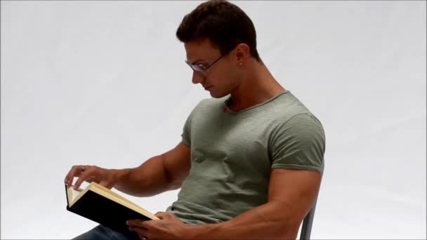 Attractive young man reading book laughing - Video