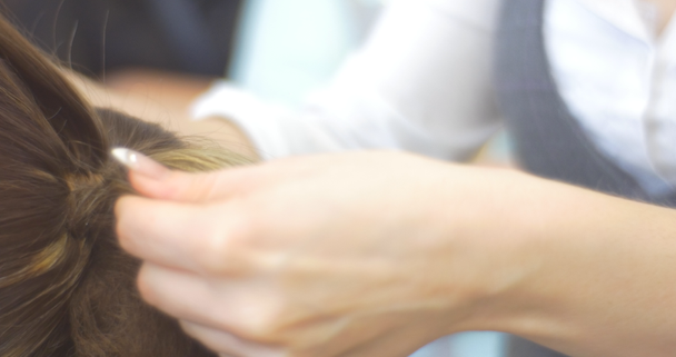 Vlasová kadeřnice je pročesat a nakonec upevňování chloupků účesu vlasová vlákna na zadním konci ženské hlavy s dlouhými vlasy kadeřnictví - Záběry, video