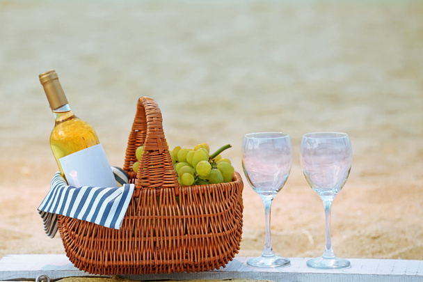 Picnic basket with bottle of wine on sand beach - Foto, Imagen