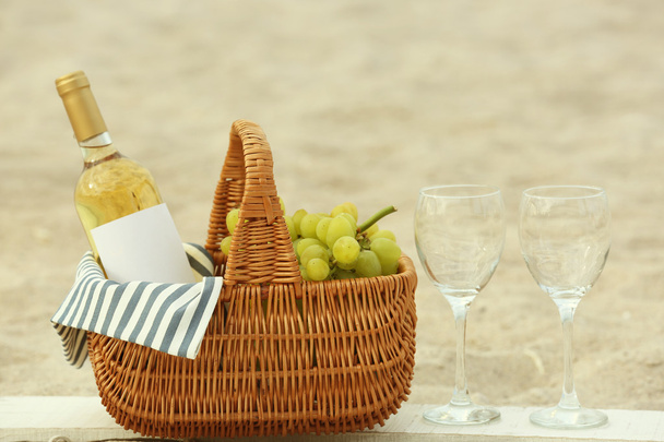 Picnic basket with bottle of wine on sand beach - Foto, Bild